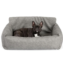 a cute black french bulldog laying on a grey car dog bed in a white room