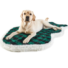 A Labrador retriever laying on a white furry dog bed with green and black checkered pattern