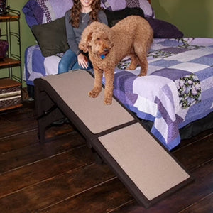 a fluffy brown going down the bed through a chocolate Pet Gear extra Wide Dog Ramp with Supertrax with a woman sitting on the bed next to him