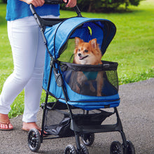 a woman walking her tiny dog inside a blue dog stroller in the park