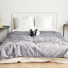a french bulldog laying on a whited bed on a grey and white fluffy dog blanket on a modern bedroom with bedside table and lamp