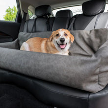 a cute little puppy laying on a grey car dog bed at the back seat of a car with black leather seats