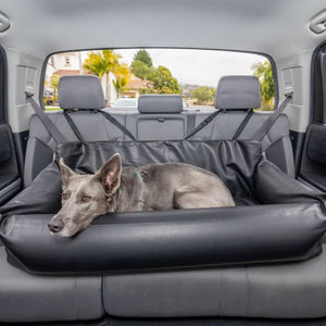 a big grey dog laying a black leather car dog bed at the backseat of the car 