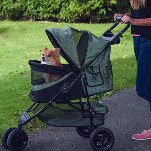a woman walking her dog in a sage colored dog stroller in the park