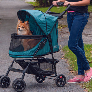 a woman walking her tiny dog inside a green dog stroller in the park