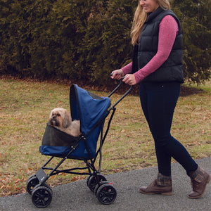 a woman walking her dog in the park in a blue dog stroller