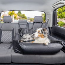 a dapple fluffy dog laying on a black leather dog bed at the back seat of a car 