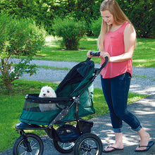 a woman walking her dog on a pine green dog stroller in the park