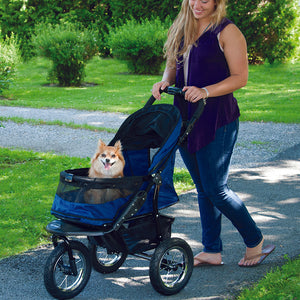 a woman walking her dog on a blue dog stroller in the park