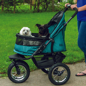 a woman walking her dog inside a pine green dog stroller on the sidewalk