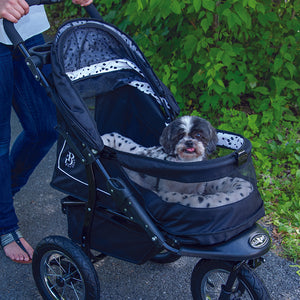 a close up image of a woman walking her tiny dog inside a dalmatian stroller