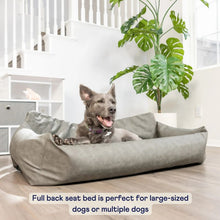 a cute grey dog laying on a grey dog car bed next to a white stairs with white drawers and a potted plant on the back 