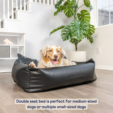 a dapple colored dog laying on a black leather car dog bed next to white potted plant and a white stair