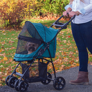 a woman walking her dog in the park in a green dog stroller
