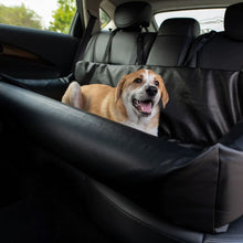 a cute tiny dog laying on a black leather car dog bed at the back seat of the car 