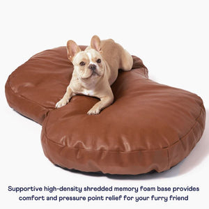a french bulldog laying on a brown leather dog bed 