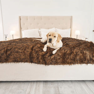 a labrador retriever laying on a brown furry dog blanket on top of a modern white bed 