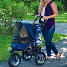 a woman walking her dog on a blue dog stroller in the park