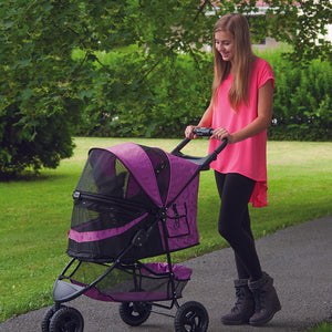 a woman walking her dog in a pink colored dog stroller in the park