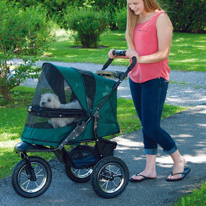 a woman walking her dog on a pine green dog stroller in the park