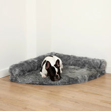 a french bulldog sleeping on a grey furry dog bed at the corner of a white wall and wooden floor