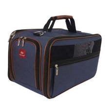 a close up image of a denim dog carrier with brown accents and handle