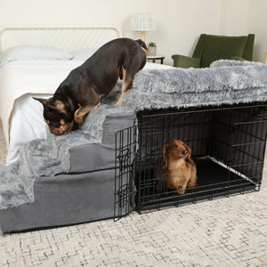 a french bulldog going down the bed by a grey fluffy bedside sleeper and a fluffy dachshund sitting inside a black steel crate