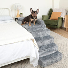 a french bulldog sitting on a fluffy grey bedside sleeper next to a white bed and an olive green chair and a white lamp on the back