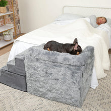 a woman sleeping on a white bed and her french bulldog sleeping on a grey fluffy bedside sleeper in a white bedroom setting