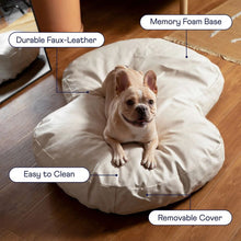 a french bulldog laying on a cream colored dog bed on a wooden floor next to a wooden couch