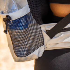 close up view of a side pocket dog a white dog backpack carrier with water bottle on it 