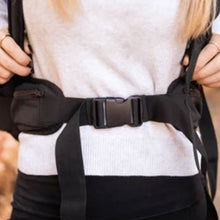 a close up image of a lady wearing a backpack carrier with safety lock around her waist attached 