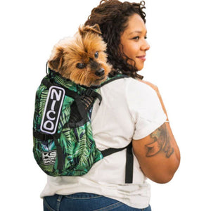 a lady in white carrying her dog in her back inside a jungle green dog backpack