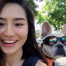 close up selfie of a lady outdoors and her dog on her back wearing a black dog googles 