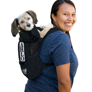 a lady in blue carrying her dog in a black dog backpack