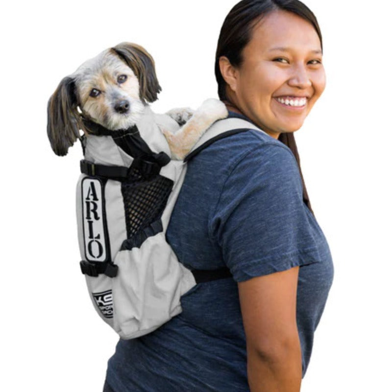 a lady in blue carrying her dog in a white dog backpack