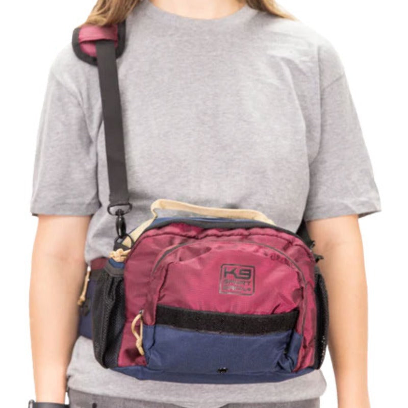 a woman wearing grey shirt wearing a red shoulder and hip bag 