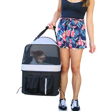 a woman carrying her dog inside a black and white dog carrier 