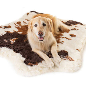A Golden retriever laying on a soft white furry curved dog bed with brown cow hide pattern