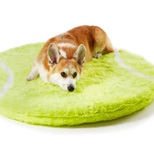 A corgi laying on a tennis ball shaped dog bed 