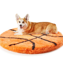 A corgi laying on a furry basketball shaped dog bed 
