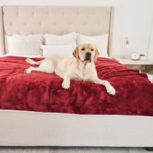 A labrador retriever on a white bed with pillows laying on a waterproof red velvet dog blanket with a tiny lamp and an alarm clock on the background