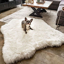 A French Bulldog laying on a big white curved dog bed that looks like a polar bear hide next to a wooden table and black cabinets on a modern setting