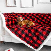A dacshund on a white couch laying on a red and black checkered pattern waterproof dog blanket and some painting frames on the wall background 