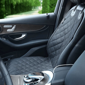 An image of a black dog car seat right next to a car window  with pine bushes on the background