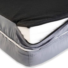 An open zipper on the edge of a gray dog bed with black top cover
