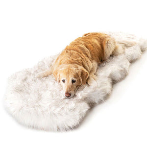 A top view of a curved furry white dog bed with a golden retriever laying on it 