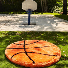 A basketball shaped dog bed on grass in front of a kiddie basketball ring with blue net 
