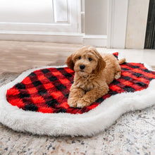 A golden doodle laying on a dog bed with red and black checkered pattern in a modern room setting