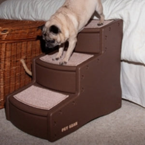 A close up image of a pug getting of bed through a three step chocolate colored dog step next to a basket 